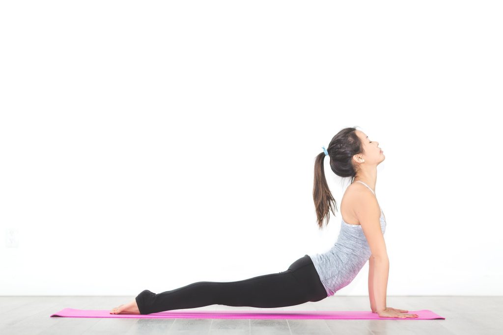 femme faisant une figure de yoga sur tapis de gym